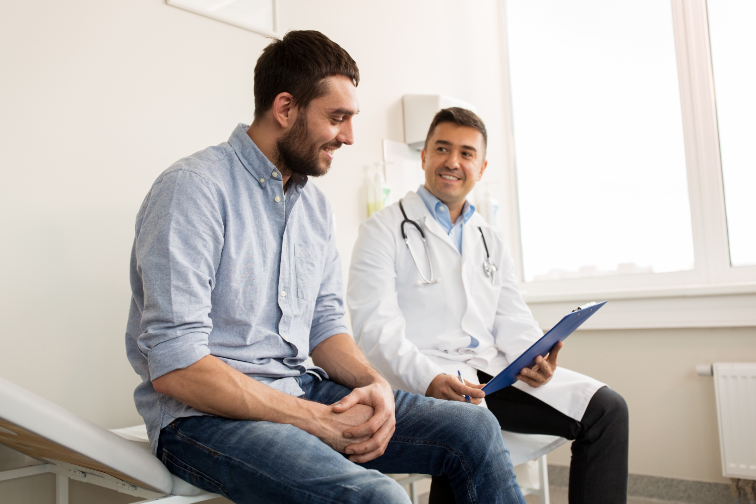image of man sat on examination tabel talking with his doctor